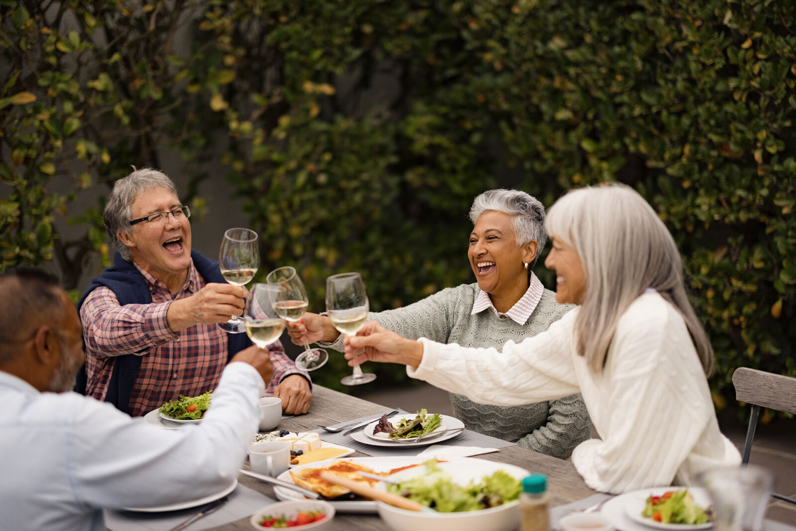 Friends celebrating together with laughter and toasting drinks.